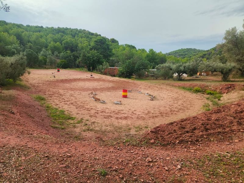 Sandreitplatz, umgeben von Olivenbäumen und bewaldeten Hügeln
